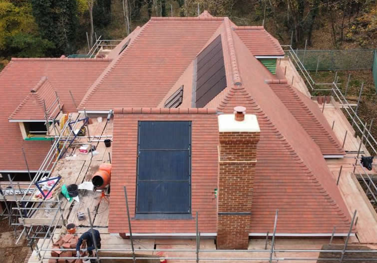Roof installation featuring retrofitted solar panels, scaffolding, and a chimney, highlighting heritage-sensitive solar integration by Precision Leadwork & Roofing Ltd.