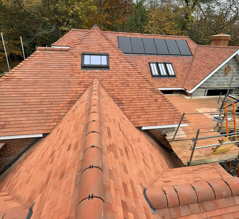 Clay tile roof installation showcasing varied tones and textures, featuring skylights and traditional craftsmanship, emphasizing longevity and aesthetic appeal for heritage properties.
