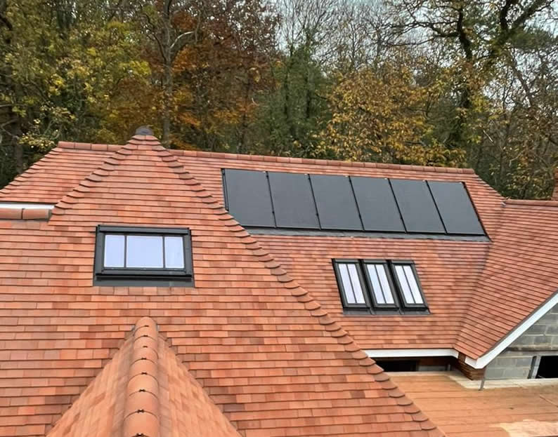 Integrated solar panels on a sloped roof with terracotta tiles, blending seamlessly with the architectural design, surrounded by autumn foliage.