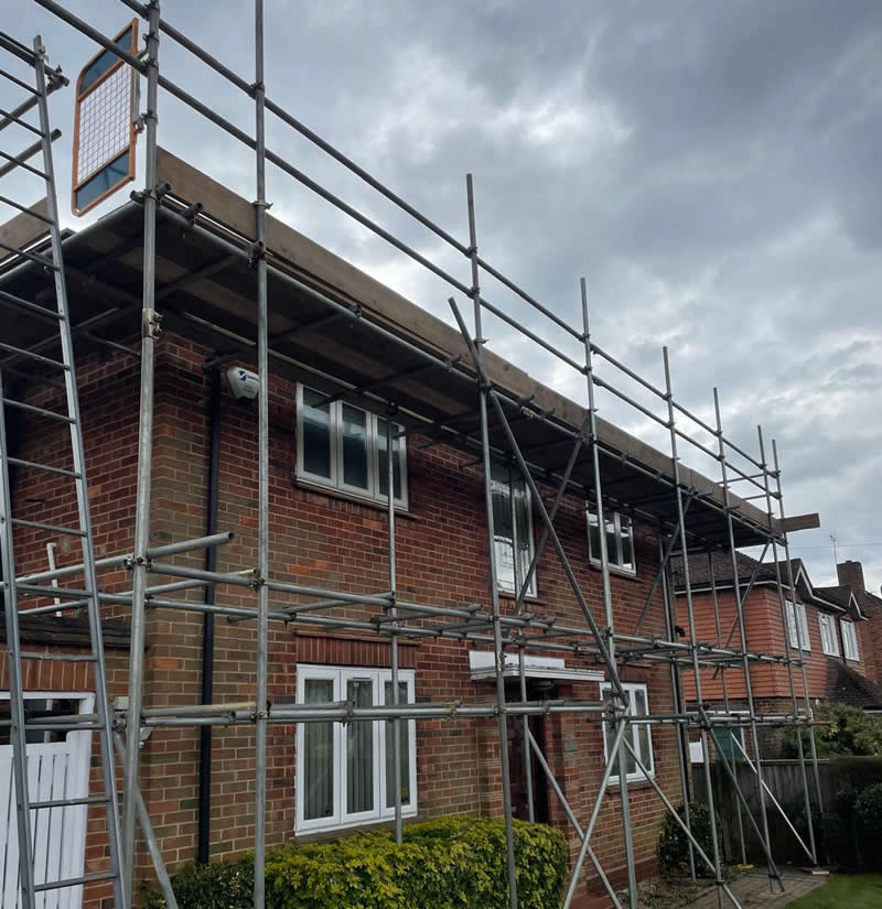 Scaffolding structure surrounding a residential building, providing safe access for roofing and restoration work, with secure platforms and edge protection.