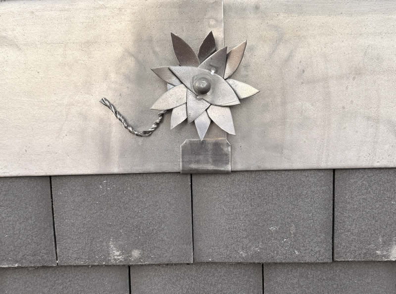 Metal floral design element attached to a zinc roofing panel, showcasing bespoke craftsmanship in hard metal roofing solutions.