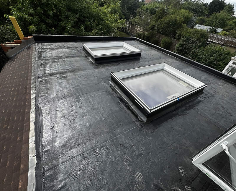 Flat roof with single-ply membrane, featuring two skylights, showcasing modern roofing solution and attention to drainage design.
