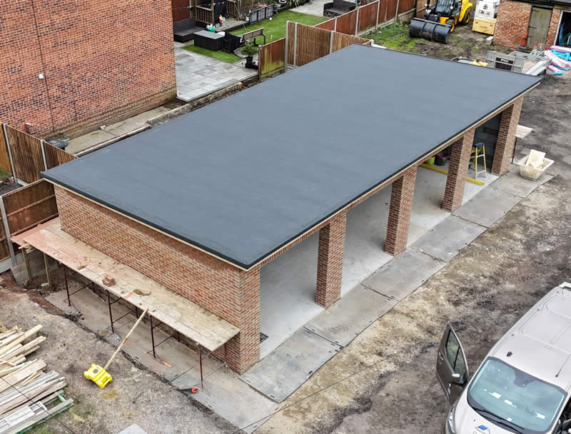 High-performance flat roof installation featuring three-layer felt system on a brick structure, surrounded by construction materials and scaffolding, illustrating durable roofing solutions for residential and commercial properties.