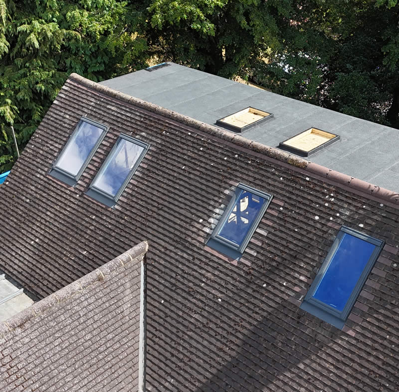Roof with modern Velux windows, showcasing energy-efficient design and integration with existing slate roofing, highlighting architectural aesthetics and minimal maintenance.