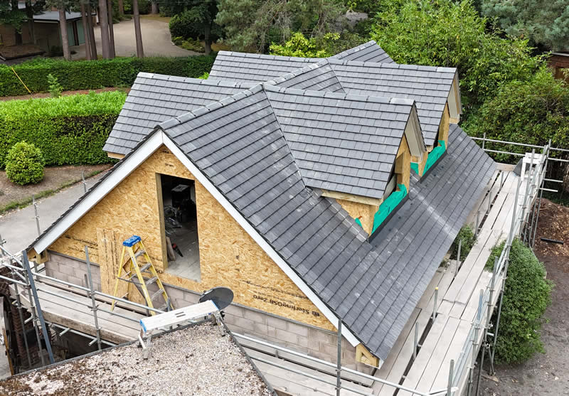 Newly installed large concrete tile roofing on a modern residential property under construction, showcasing scaffolding and structural elements, emphasizing durability and weather resistance.