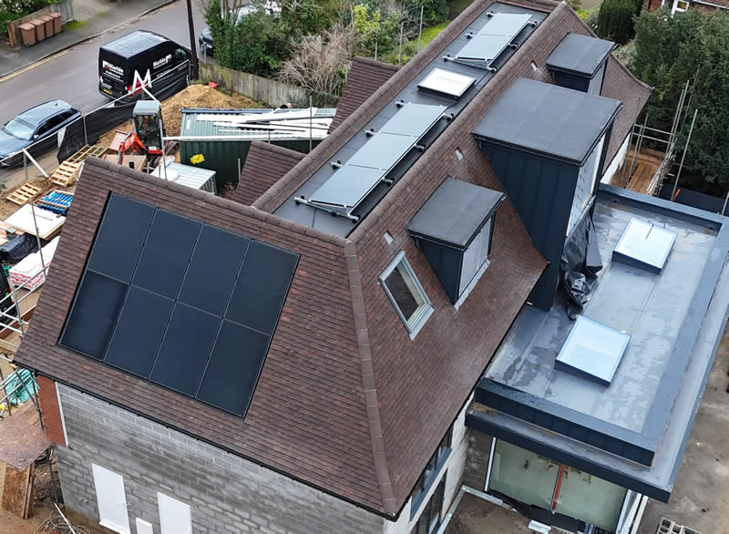 Integrated solar panels installed on a modern roof, showcasing a flush design that complements the architectural style, surrounded by construction materials and equipment, emphasizing energy efficiency and aesthetic appeal in high-value properties.
